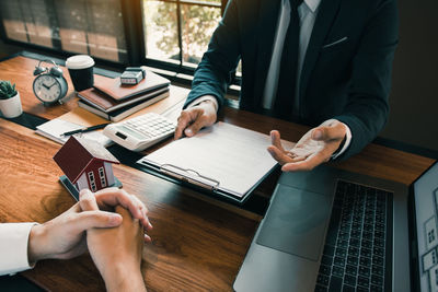 Midsection of man using mobile phone while sitting on table