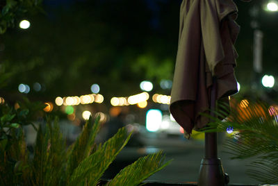 Low section of woman in illuminated city at night