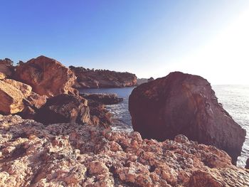 Rock formations by sea against clear sky