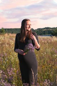 Beautiful woman standing on field against sky