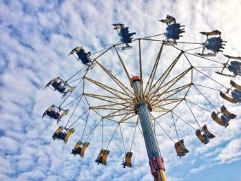 Low angle view of chain swing ride against cloudy sky