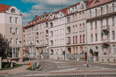 Road by buildings in city against sky