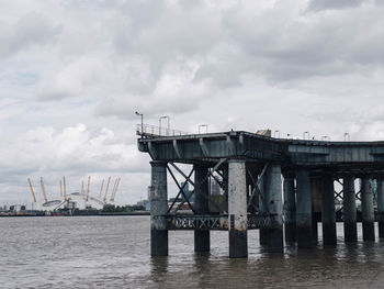 Incomplete bridge over river against sky