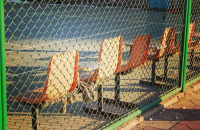 Empty chairs in court seen through chainlink fence