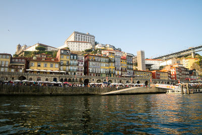 Boats in river by buildings against clear sky