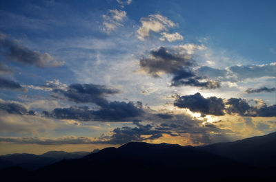 Low angle view of silhouette mountains against dramatic sky