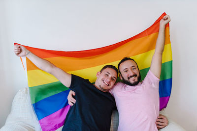 Two homosexual men holding lgbtq flag.