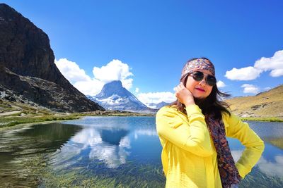 Woman wearing sunglasses standing against lake and sky