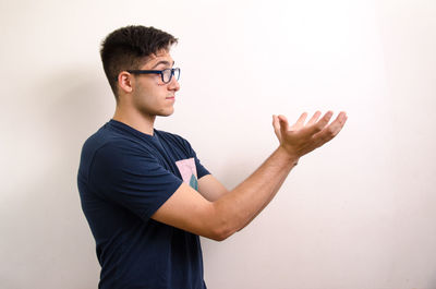 Side view of young man looking away against white background