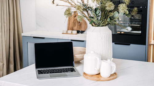 Home office setup with laptop and cozy kitchen decor. a chic home office setup 