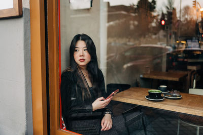 Young woman using mobile phone while sitting on table