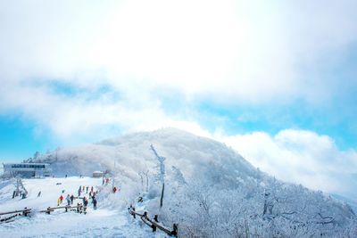 People on snow covered mountain against sky