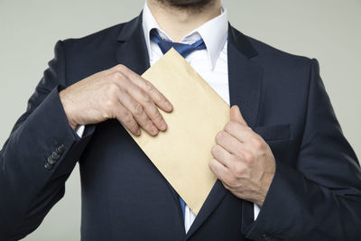 Midsection of man holding umbrella against white background