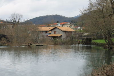 Houses by lake and buildings against sky