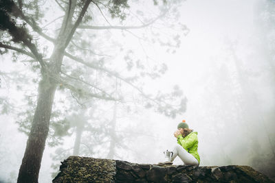 Man sitting on tree in forest