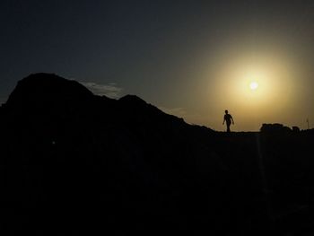 Silhouette man standing on mountain against sky during sunset