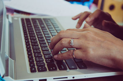 Cropped image of hands using laptop in office