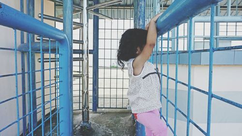 Side view of girl climbing on fence