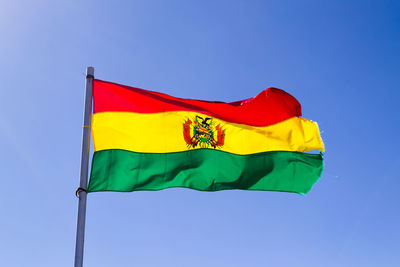 Low angle view of flags flag against clear blue sky