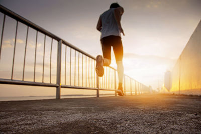 Man on bridge against sky during sunset