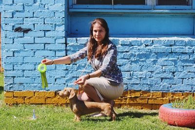 Happy woman with dog against wall