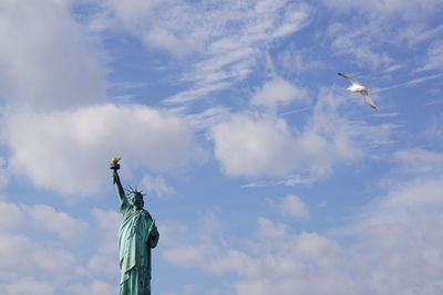 Low angle view of seagull flying against cloudy sky