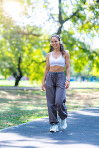 Full length of young woman standing against trees