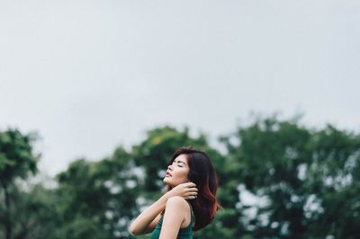 Portrait of smiling young woman looking away against sky