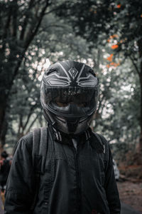 Portrait of person wearing hat standing against trees