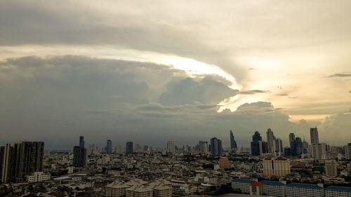 Aerial view of cityscape against cloudy sky