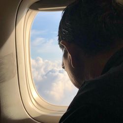 Portrait of man looking through airplane window