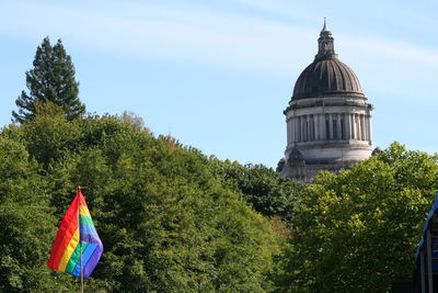 Rainbow flag against trees and state capitol building