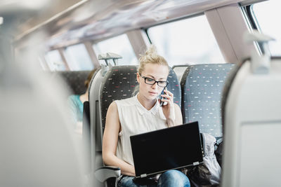 Young woman using mobile phone in car