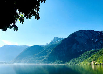 Scenic view of lake and mountains against clear blue sky