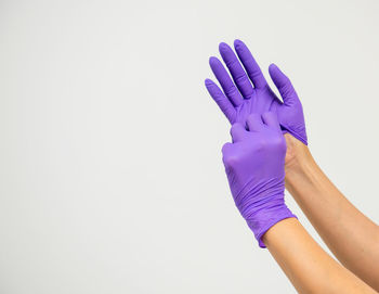 Close-up of hand holding purple over white background