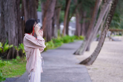 Side view of woman standing on mobile phone outdoors