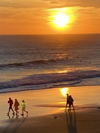 People walking on beach during sunset