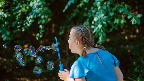 Side view of young woman standing against plants