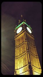 Low angle view of clock tower at night