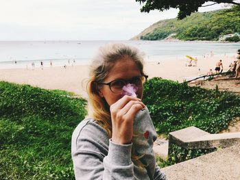 Portrait of woman smelling flower against sea