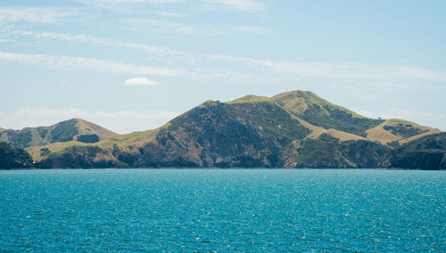 Scenic view of sea by mountains against sky