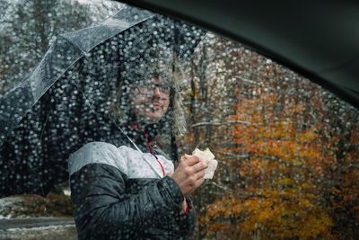 Man with umbrella standing in forest during rainy season