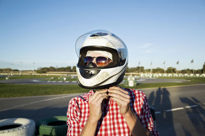 Close-up of man wearing helmet while standing at motor racing track