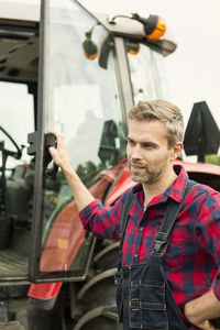 Man with hand on hip standing by tractor