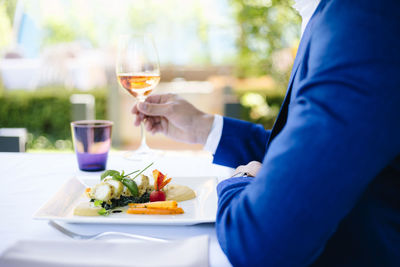 Midsection of man holding drink at restaurant