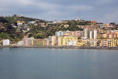 Buildings by sea against sky in city