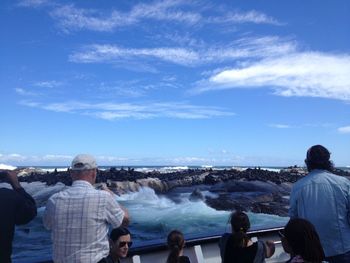 Rear view of people looking at sea against sky