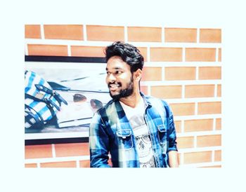 Portrait of smiling man standing against wall