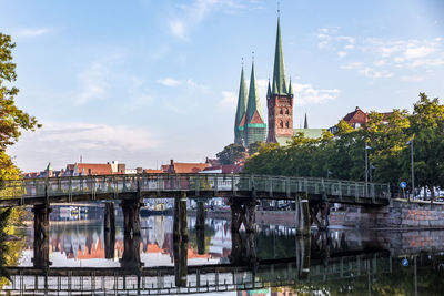 Bridge over river by buildings against sky in city