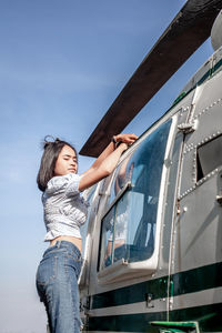 Low angle view of woman standing on airplane against sky